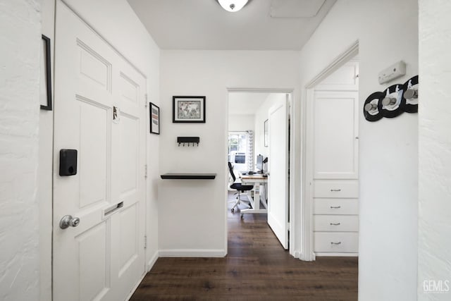 corridor featuring baseboards and dark wood-type flooring