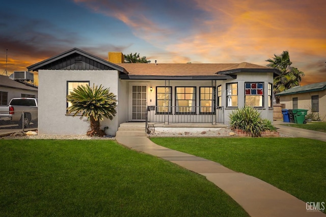 view of front facade featuring a yard, fence, a porch, and stucco siding