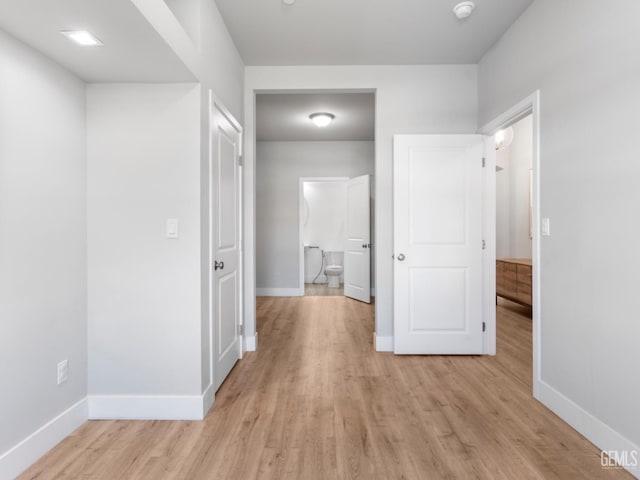 corridor featuring light wood-style flooring and baseboards