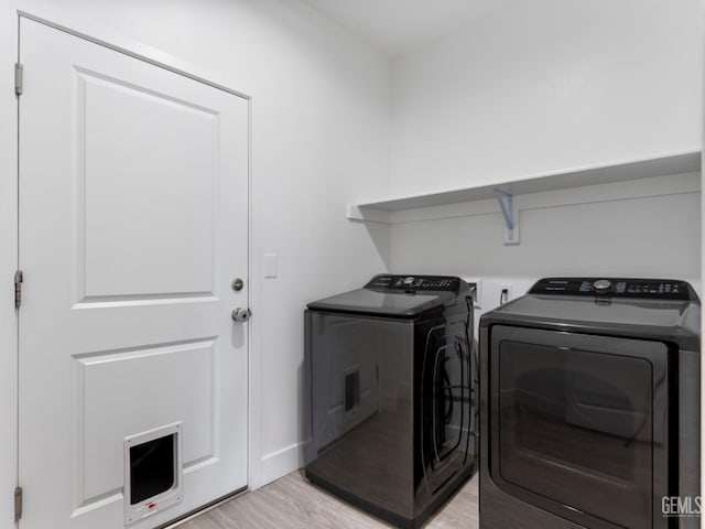 washroom with light wood-style floors, laundry area, and independent washer and dryer