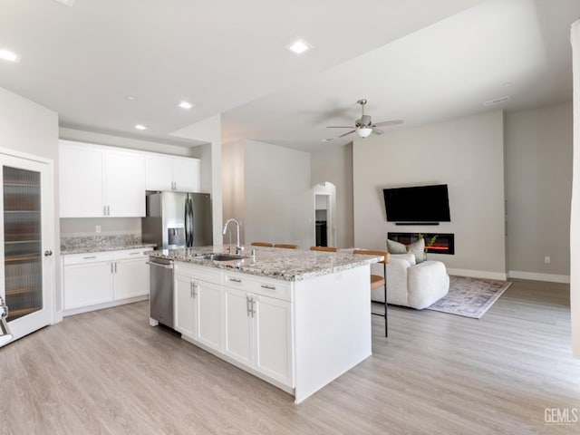 kitchen with a kitchen island with sink, appliances with stainless steel finishes, a sink, and white cabinetry