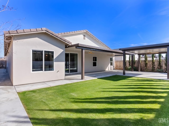 back of house featuring a lawn, ceiling fan, fence, a patio area, and stucco siding