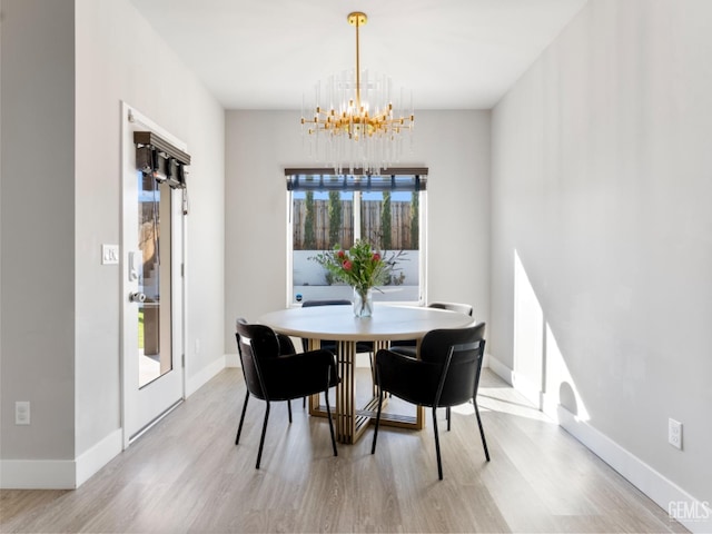 dining room featuring light wood-style floors, baseboards, and an inviting chandelier