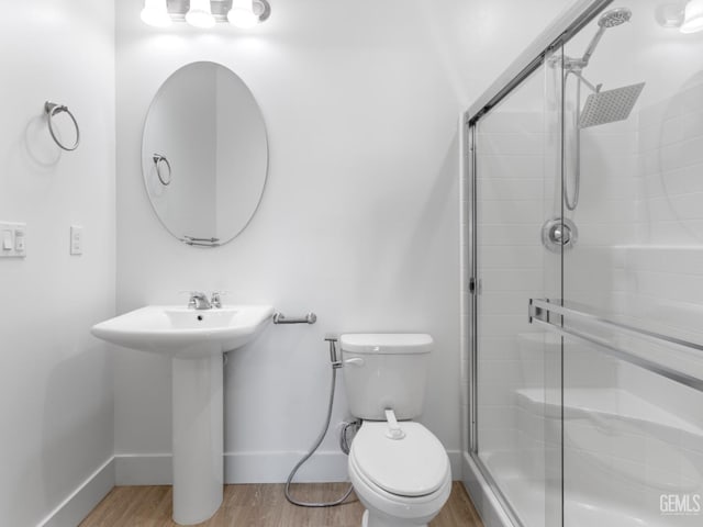 full bathroom featuring toilet, a sink, wood finished floors, baseboards, and a stall shower