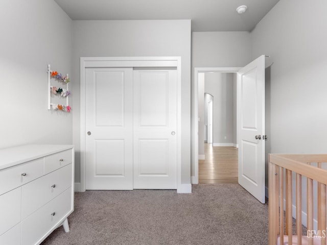 unfurnished bedroom featuring baseboards, a closet, and light colored carpet