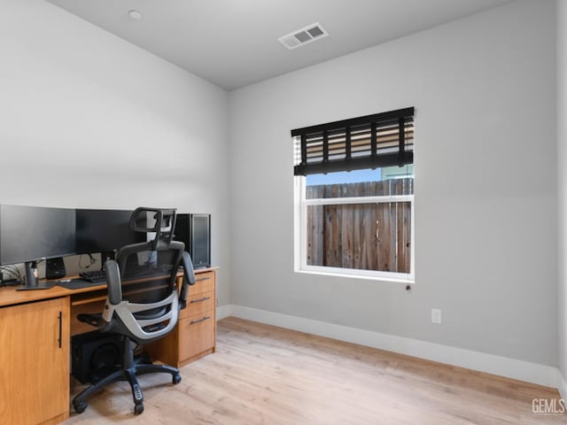 office featuring baseboards, visible vents, and light wood finished floors