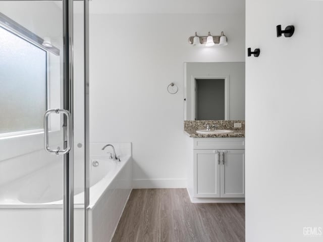 bathroom featuring a garden tub, a shower with shower door, vanity, wood finished floors, and baseboards