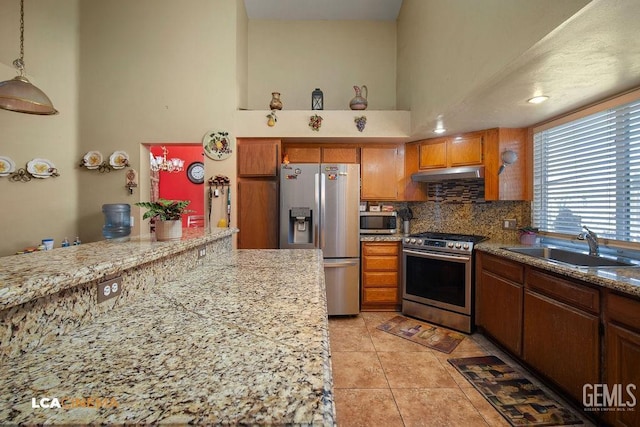 kitchen featuring a high ceiling, appliances with stainless steel finishes, pendant lighting, sink, and light tile patterned flooring