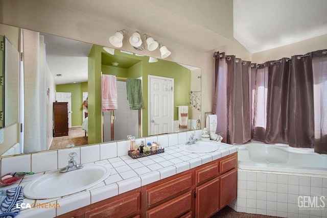 bathroom featuring tiled tub, lofted ceiling, and vanity