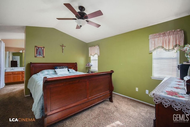 carpeted bedroom featuring ceiling fan, ensuite bath, vaulted ceiling, and multiple windows