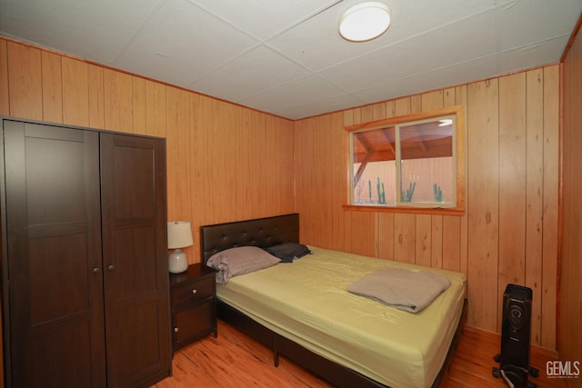 bedroom with wood walls, light hardwood / wood-style flooring, and a closet