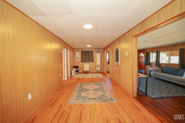 corridor featuring light wood-type flooring and wood walls