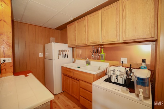 clothes washing area with wooden walls, light wood-type flooring, and washer / clothes dryer