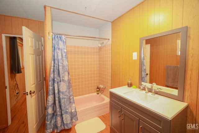 bathroom with vanity, wood walls, and shower / bathtub combination with curtain