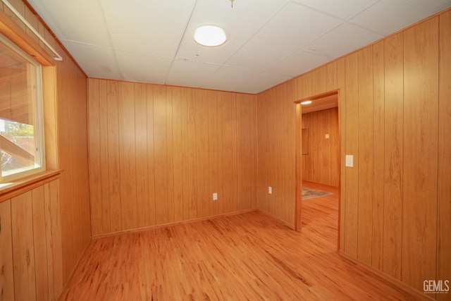 unfurnished room featuring wooden walls and light hardwood / wood-style floors