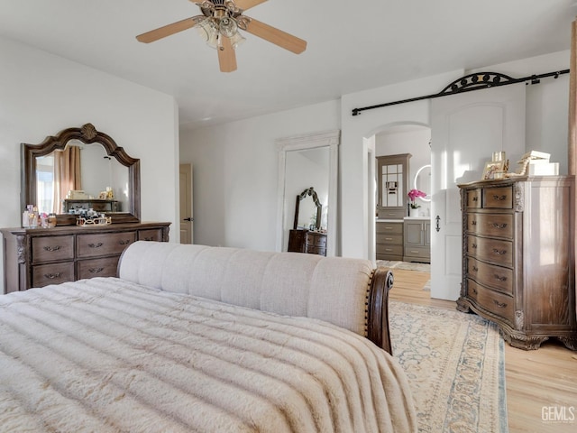 bedroom featuring ensuite bath, light hardwood / wood-style floors, and ceiling fan