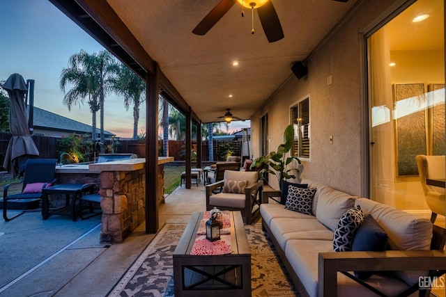 patio terrace at dusk featuring an outdoor living space, ceiling fan, and a bar