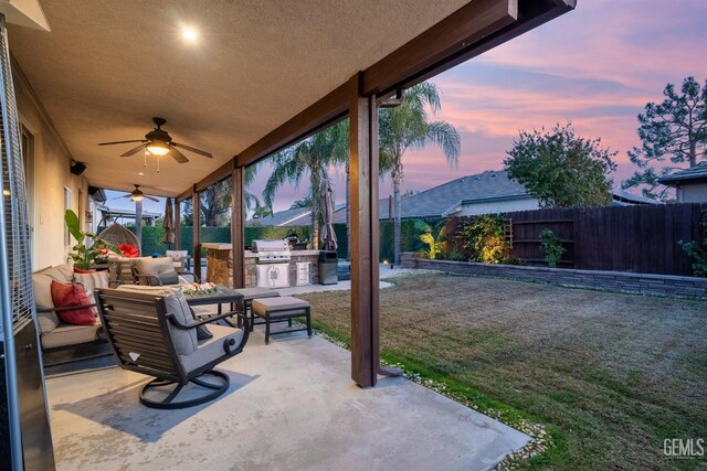 patio terrace at dusk with an outdoor living space, area for grilling, a yard, and ceiling fan