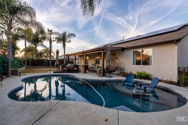 pool at dusk with outdoor lounge area and a patio area