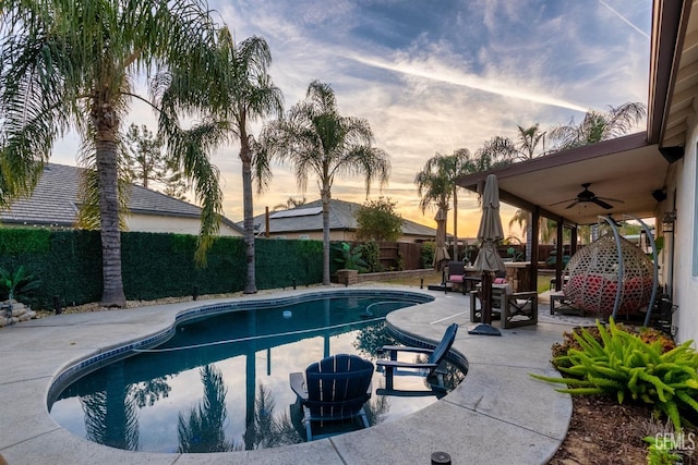 pool at dusk with ceiling fan and a patio