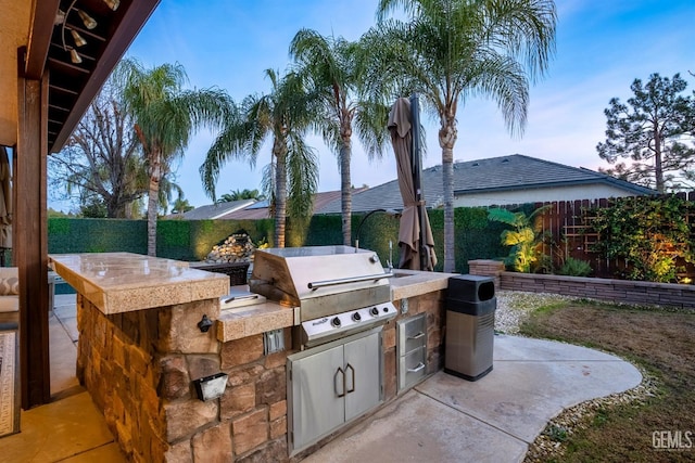 patio terrace at dusk featuring area for grilling and a grill