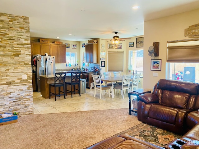 carpeted living room featuring ceiling fan and sink