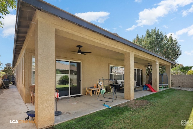 rear view of property with ceiling fan, a patio area, and a yard