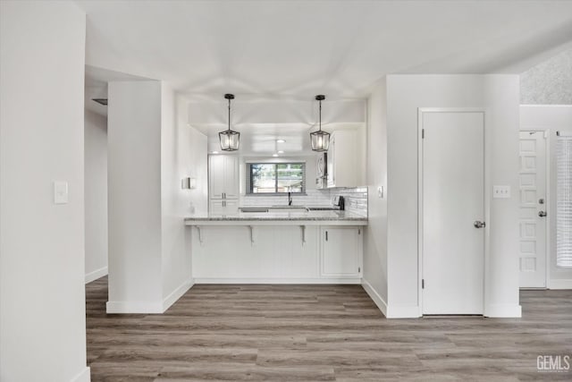 3112 Harrogate Ln, Bakersfield, CA 93309 - kitchen featuring wood finished floors, white cabinets, a breakfast bar, and backsplash