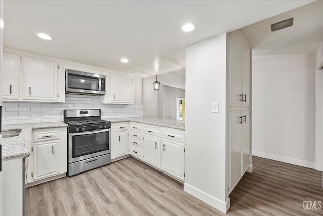 3112 Harrogate Ln, Bakersfield, CA 93309 - kitchen with appliances with stainless steel finishes, light wood finished floors, white cabinets, decorative backsplash, and light stone countertops