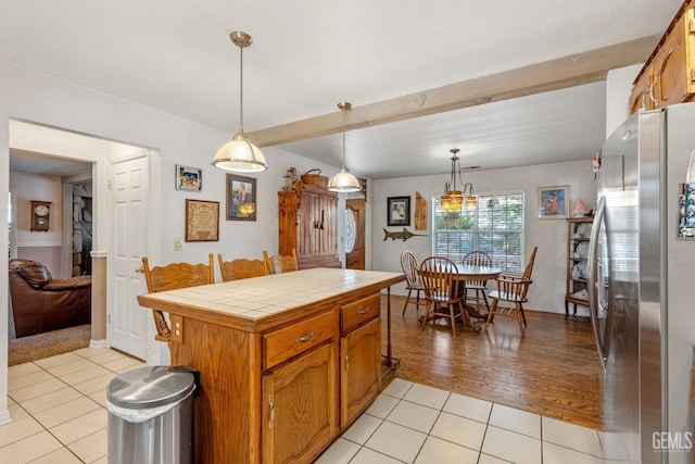 kitchen featuring pendant lighting, tile countertops, stainless steel refrigerator, and light tile patterned flooring