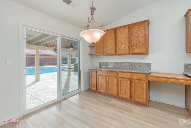 kitchen featuring built in desk, hanging light fixtures, vaulted ceiling, and light wood-type flooring