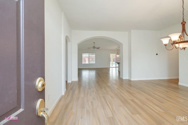 interior space featuring ceiling fan with notable chandelier and light hardwood / wood-style floors