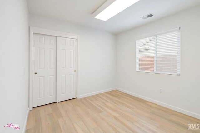 unfurnished bedroom with light wood-type flooring and a closet