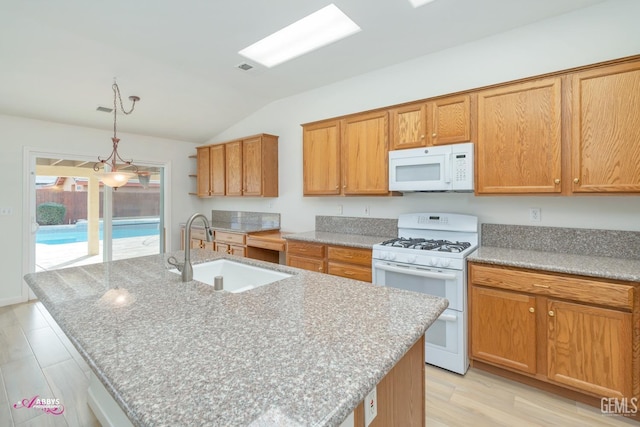 kitchen with white appliances, lofted ceiling with skylight, a kitchen island with sink, and sink