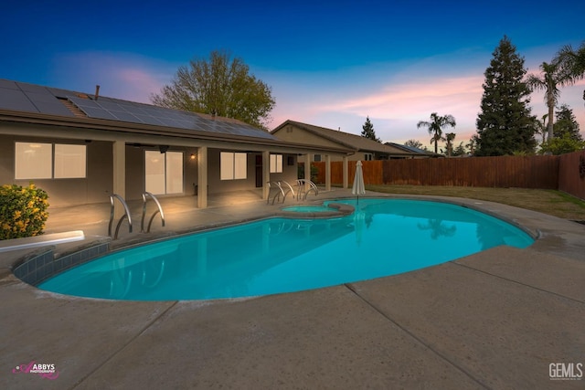 pool at dusk featuring an in ground hot tub and a patio