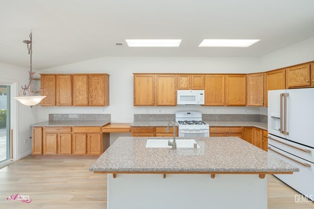 kitchen with sink, hanging light fixtures, an island with sink, white appliances, and a breakfast bar