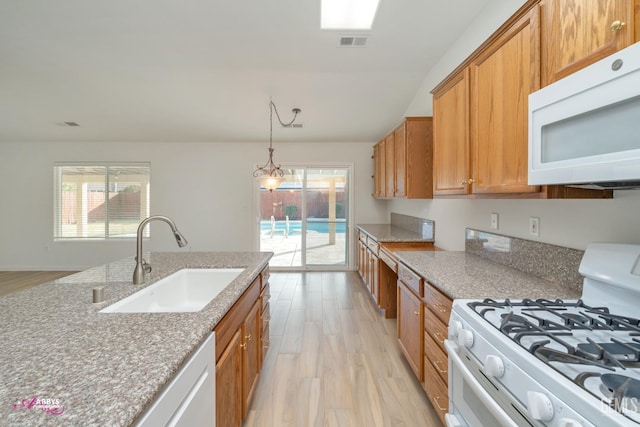 kitchen with light wood-type flooring, white appliances, hanging light fixtures, and sink