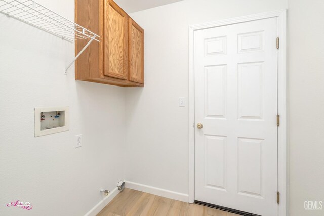 washroom with hookup for a washing machine, cabinets, and light hardwood / wood-style floors