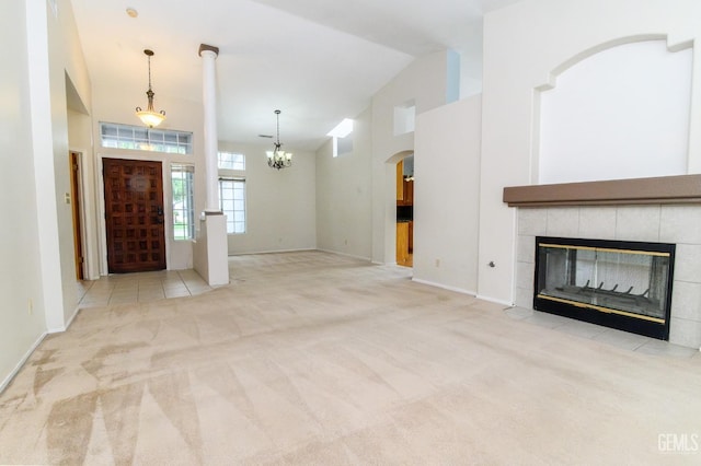 unfurnished living room featuring light colored carpet, high vaulted ceiling, and a tiled fireplace