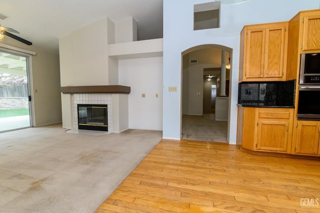 kitchen with ceiling fan, decorative backsplash, light carpet, and a tile fireplace