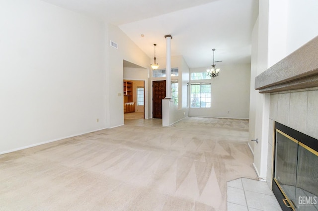 unfurnished living room with a fireplace, light carpet, high vaulted ceiling, and a notable chandelier