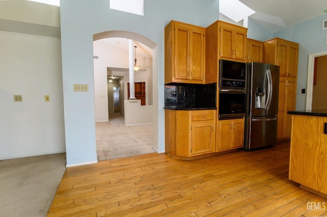 kitchen with decorative backsplash, stainless steel refrigerator with ice dispenser, wall oven, light hardwood / wood-style flooring, and lofted ceiling