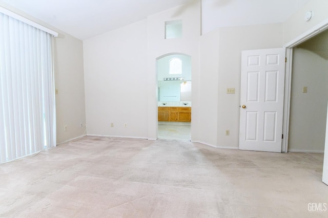 spare room with light carpet and vaulted ceiling