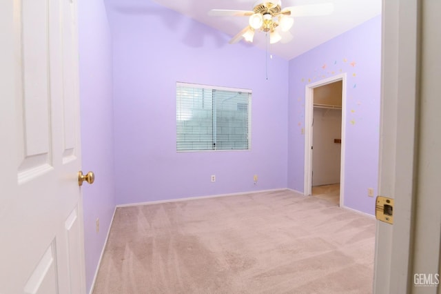 unfurnished bedroom featuring ceiling fan, light colored carpet, a walk in closet, and a closet