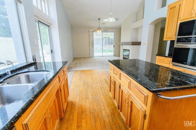 kitchen featuring ceiling fan, stainless steel oven, a center island, sink, and decorative light fixtures