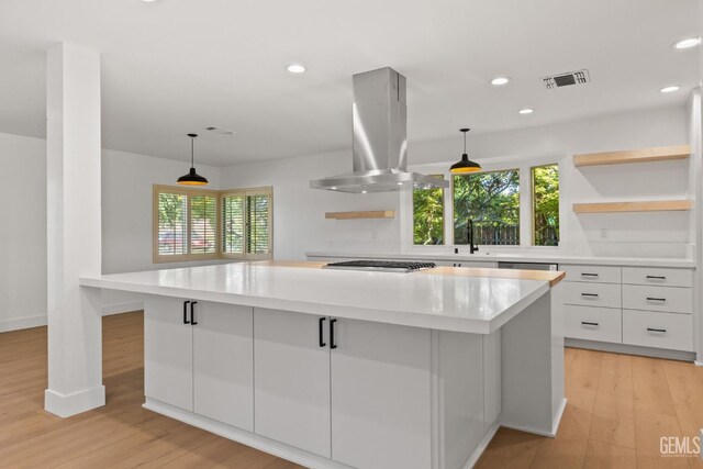 2330 Myrtle St, Bakersfield, CA 93301 - kitchen with island range hood, a kitchen island, white cabinetry, stainless steel gas stovetop, and light countertops