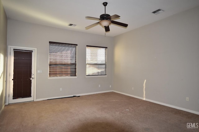 spare room featuring carpet, visible vents, and baseboards