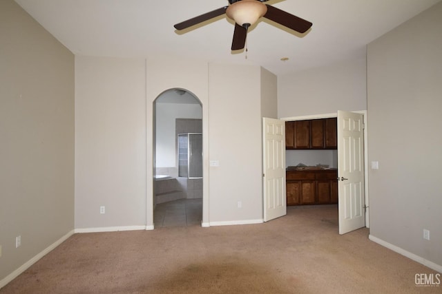 unfurnished room featuring a ceiling fan, arched walkways, light carpet, and baseboards