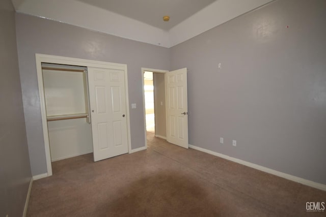 unfurnished bedroom featuring carpet floors, a closet, and baseboards