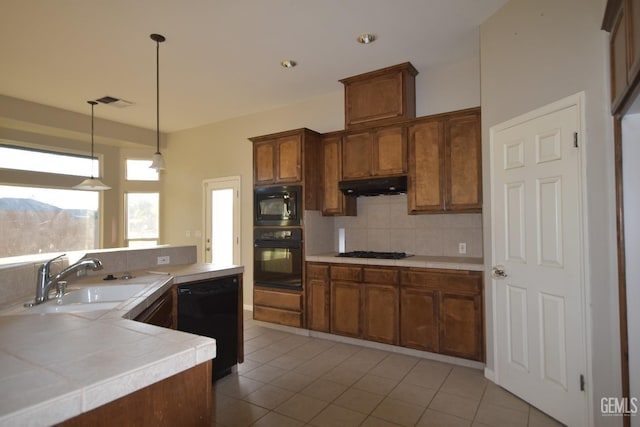 kitchen featuring light tile patterned floors, a sink, under cabinet range hood, black appliances, and backsplash